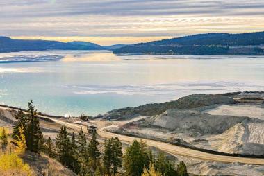Mining site in British Columbia with sparkling blue water and mountains on the horizon