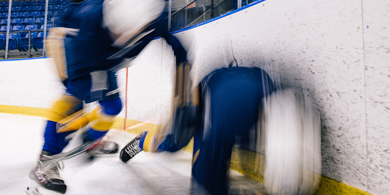 A collision between two hockey players is shown with a blurred effect, capturing the speed at which impacts can occur