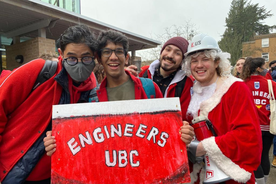 Mayank and his friends, holding up a Engineers UBC sign while wearing red outfits