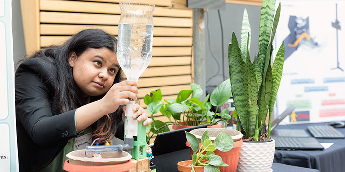 Student adjusting a watering mechanism for plants 