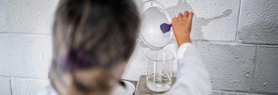Woman in lab pouring a clear liquid into a beaker
