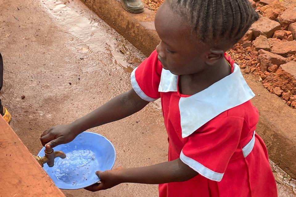 Student at a Kenyan school rinses her bowl under clean running water