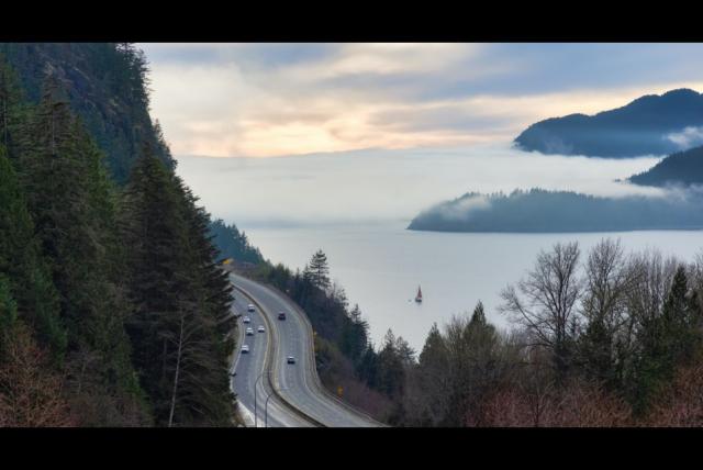 Image of a highway on the edge of the mountain. Sea in the background.