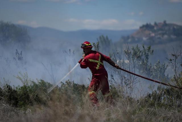 Firefighter in a field putting out fire with smoke in the air