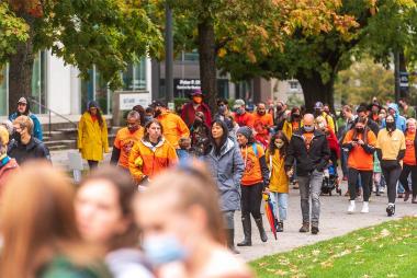 A crowd of people in orange shirts march down Main Mall on the University of British Columbia Vancouver campus for the National Day for Truth and Reconciliation