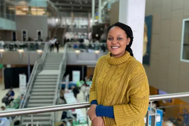 Chadia Uwamahoro in a yellow sweater, smiling at camera
