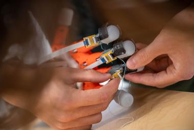 Human hands adjusting sensors on the fingers of a robotic hand