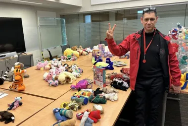 Dr. Ray Taheri stands next to tables full of stuffed toys