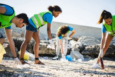 People wearing green vests cleaning up a beach
