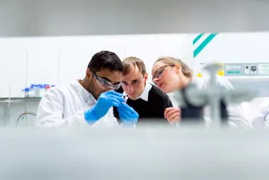 Three people in a lab looking 