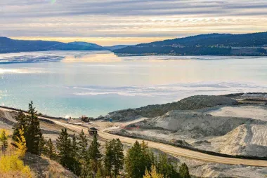 Mining site in British Columbia with sparkling blue water and mountains on the horizon