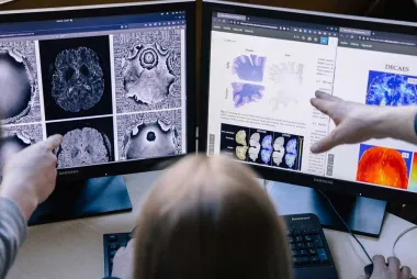 Researchers looking at brain scans on two computer screens