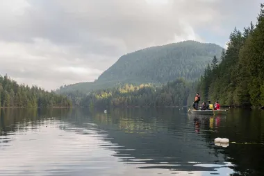 People on a boat in a BC lake with a mountain in the background