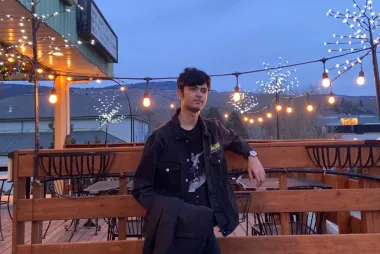 Preeyansh taking a photo at dusk, in front of lit up Christmas lights