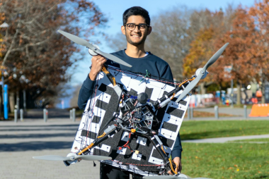 Aman holding his drone that he built with his engineering design team, on Main Mall