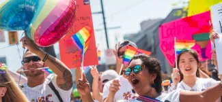 A group of people marching at the pride parade with UBC signage