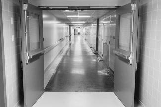 A black and white image of a long narrow and empty hospital hallway