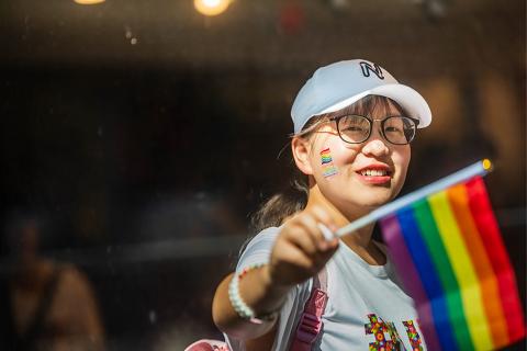 UBC student at a pride parade in 2019 waving the pride flag.