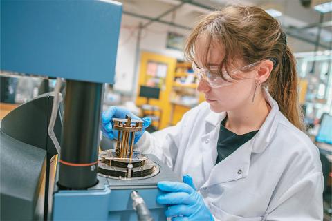 A girl in lab gear working with materials in the lab.