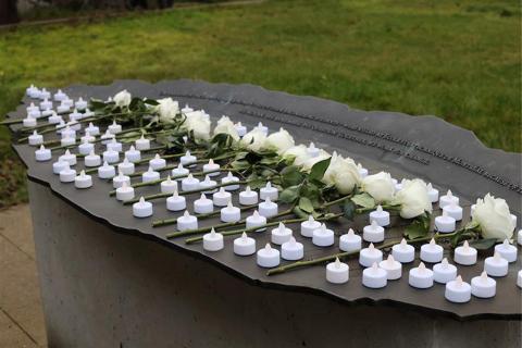 Fourteen white roses and candles on a permanent memorial at UBC Vancouver.