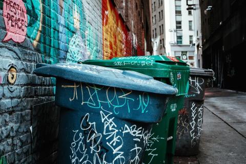 A row of garbage bins in an alley.