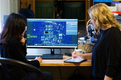 Two women look plan at a computer.