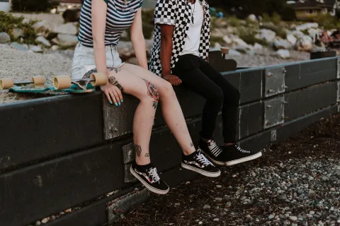 Two youths in casual clothes sit on a ledge