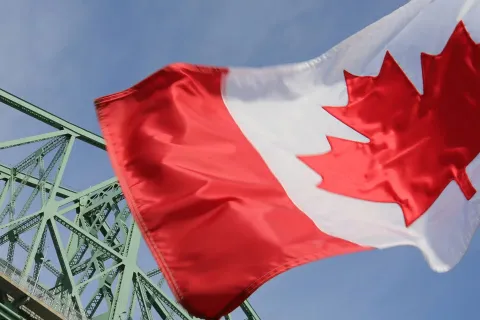 A Canadian flag waves in front of a construction crane