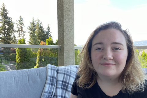 Abbey, smiling, while sitting on her balcony with trees and nature in the background