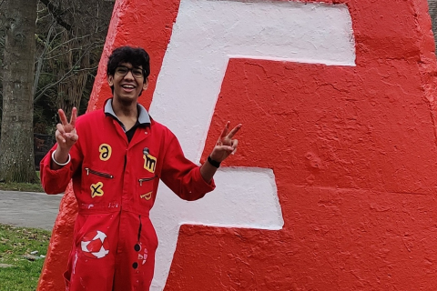 Mayank Gupta, dressed in full red color in front of the UBC Engineering Cairn