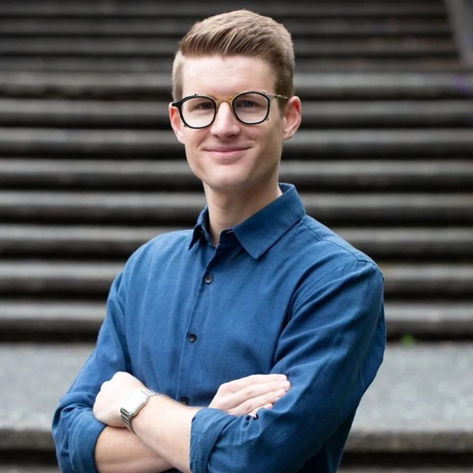 Man in glasses, folding arms in front of stone staircase