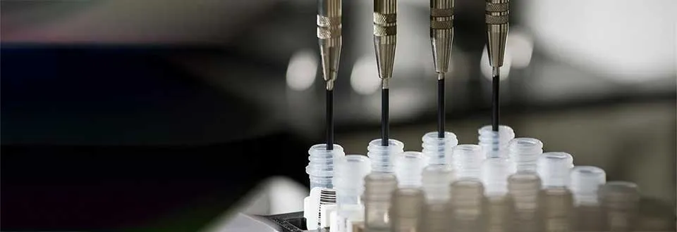 close-up of several pipette tips dispensing liquid into a rack of small, clear plastic tubes.