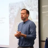 Man in blue sweater at lectern