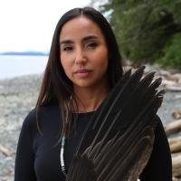 Woman on beach holding object made of blackbird feather